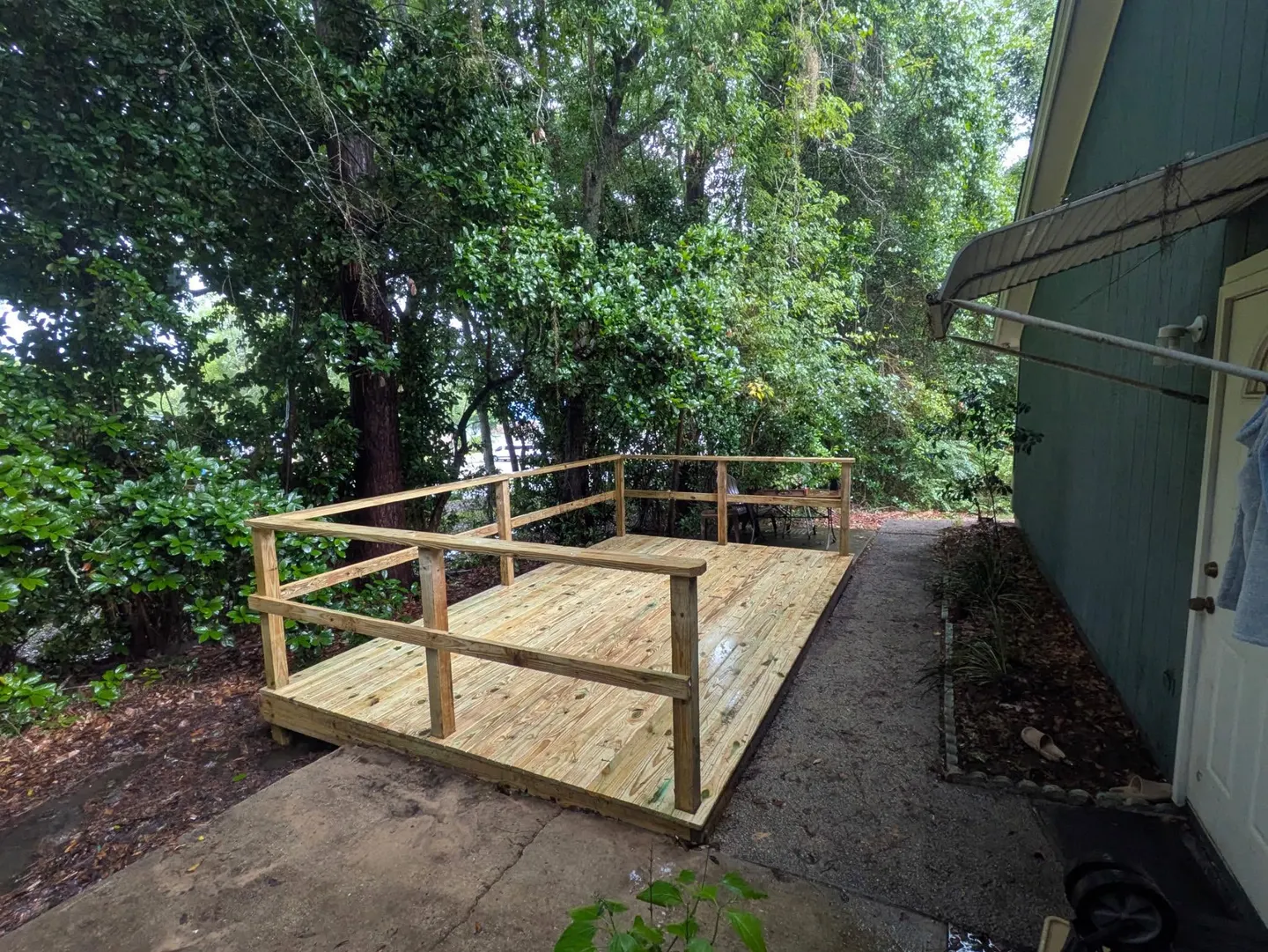 New backyard deck platform with wood railing beside a home